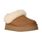The UGG Women's Tazzelle Chestnut slipper features a tan suede upper, thick beige platform sole, and fluffy cream shearling lining at the opening, shown on a white background.