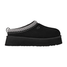 The UGG Women's Tazz II Black slipper features a thick platform sole, plush sheepskin lining, white zigzag trim around the opening, suede upper, and a pull tab at the heel.