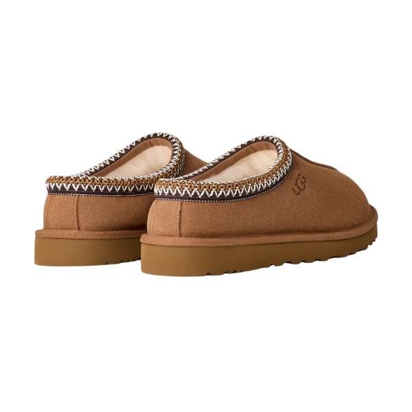 The UGG Men's Tasman II Chestnut slippers feature a brown suede upper, tan sole, patterned trim, and cozy sheepskin lining. Shown from the back and side.