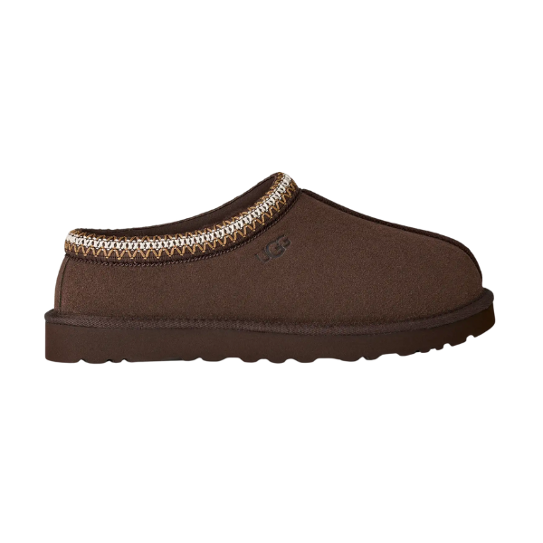 The UGG Men's Tasman II Cocoa slipper features a brown suede upper, decorative stitched trim, plush sheepskin lining, and a textured rubber sole, shown from the side.