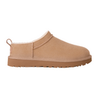 The UGG Women's Classic Micro Sand slipper by UGG is a tan suede slip-on with a thick rubber sole and white fleece lining, inspired by sheepskin boots and shown from the side on a white background.