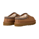 The UGG Women's Tasman II Chestnut slippers feature thick, textured soles, cozy sheepskin lining, and a decorative woven trim around the opening. They are displayed from a rear side angle.