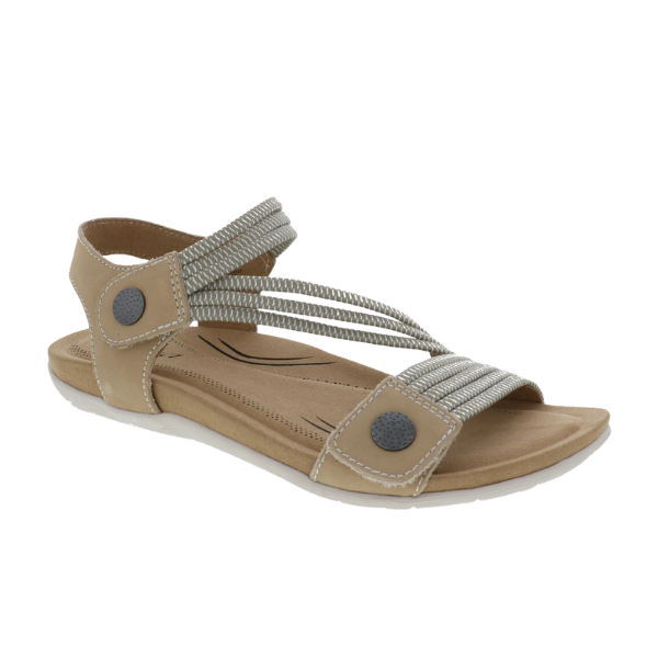 The Biza Womens Luna Sand by BIZA FOOTWEAR is a beige sandal with a flat sole, light gray elastic cross straps, and black circular side accents, designed for women seeking comfortable sandals that relieve foot pain.
