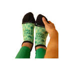 Person pulls up FEETURES Elite Light Cushion Tab Lucky Vibes socks with shamrocks and Anatomical Design on white background.