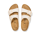 The BIRKENSTOCK Womens Arizona Birko-Flor Patent Offwhite/Eggshell sandals feature cork footbeds and adjustable buckles, offering stylish everyday comfort. Shown from above on a white background.