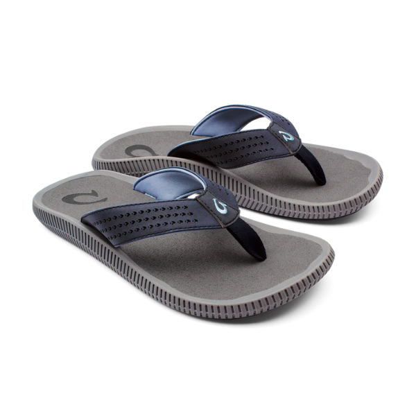 The OLUKAI Mens Ulele Dark Blue sandals feature gray, water-resistant soles with textured grip and dark blue logo straps with perforations, designed for comfort and foot pain relief, shown on a white background.