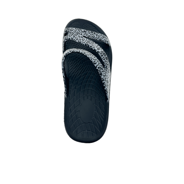 The SOVELLA Womens PF Slide Black/Leopard sandal features two white straps with a black leopard print, a textured sole, and built-in arch support—ideal for comfort and recovery—shown on a white background.