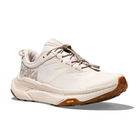The HOKA Womens Transport Wide Neutral is a beige running shoe with a chunky sole, brown tread, lace-up closure, side HOKA logo, VIBRAM outsole for grip, and is made from vegan materials.