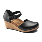 The Birkenstock Womens Mary Leather Black by BIRKENSTOCK is a stylish black wedge with a closed toe, ankle strap, and cork sole. The tan footbed bears Papillio branding, offering comfort and support for casual or dress wear.