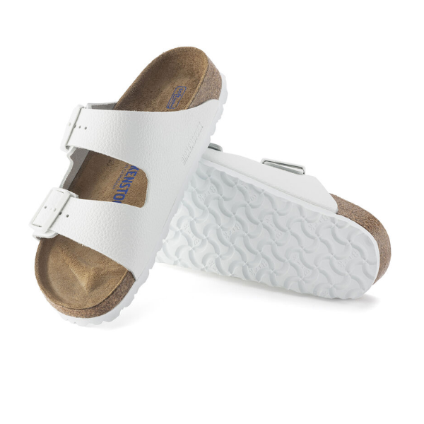 A pair of BIRKENSTOCK Womens Arizona Soft Footbed White sandals features two adjustable straps, soft footbeds for comfort, and a textured sole—one sandal shown from the top, the other highlighting the sole.