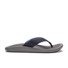 The OLUKAI Mens Ulele Dark Blue sandal features a textured gray sole and perforated dark blue strap, designed for foot pain relief and comfort, shown from the side on a white background.