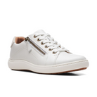 The Clarks Womens Nalle Lace White is a white leather zip-up sneaker by CLARKS with white laces, silver eyelets, side zipper, light brown lining, and white sole. It features a Contour Cushion footbed for relief and is shown on a plain white background.