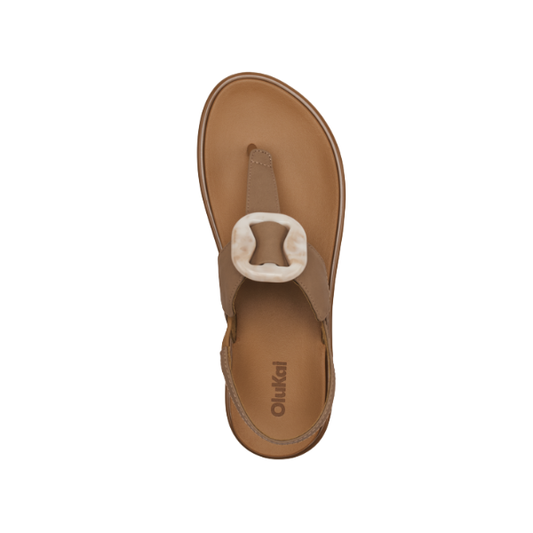 A top view of a single Olukai Womens La‘i T–Bar Tan sandal by OLUKAI, with a thong strap, large marbled white oval buckle, tan branded footbed, and design focused on style and foot pain relief.