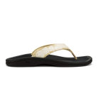 A side view of the OLUKAI Womens Ohana Toasted Coconut sandal featuring a black base, cream floral-patterned strap, water-resistant anatomical footbed, and low heel.