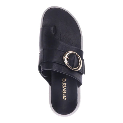 The REVERE Womens Biscay Black is a black leather toe post sandal with a Wide strap, large gold buckle, gold REVERE logo on the insole, white sole, and provides stylish arch support for comfort.
