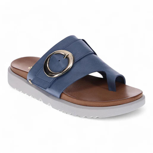 The Revere Womens Biscay Blue by REVERE is a blue sandal with a Wide strap, large round metallic buckle, premium leather, anatomically designed footbed, brown accents, white wavy sole, and a stylish open-toe loop design.