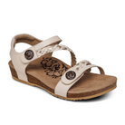 The Aetrex Womens Jillian Ivory sandal features braided and solid straps, adjustable Velcro with decorative metal buttons, a cork-textured orthotic footbed, floral insole design, and flat ridged sole for comfort.
