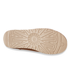 The image displays the bottom view of the UGG Mens Classic Slip-On Chestnut, featuring a tan sole with a geometric tread and the UGG logo embossed at the center—showcasing slip-on comfort and signature style.