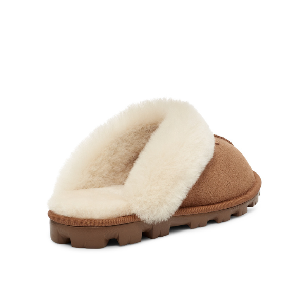 The UGG Womens Coquette Slipper in Chestnut features a plush white sheepskin lining and a textured brown rubber sole, displayed from the rear side on a white background.