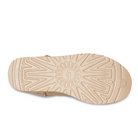 The image shows the beige sole of the UGG Womens Classic Short II Boot in Mustard Seed, featuring a textured geometric tread pattern and the engraved UGG logo at the center.