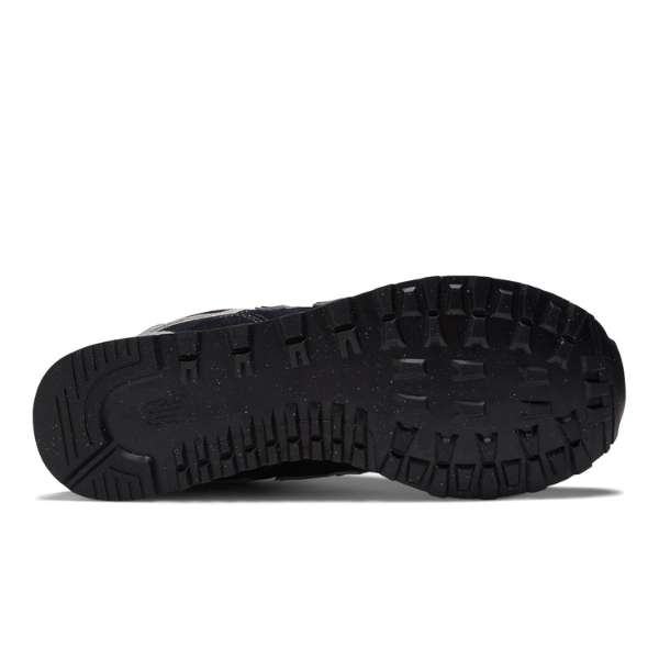 Close-up of the black rubber outsole on the New Balance Men's 574 Black/White running shoe by NEW BALANCE, featuring a rugged, textured tread for grip and traction. The sole, designed to help relieve foot pain, is shown facing up on a white background.