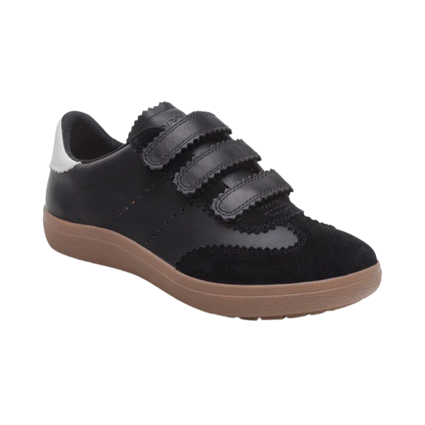 The Aetrex Women's Morgan Black by AETREX WORLDWide INC is a black sneaker with a brown sole, three Velcro straps, suede accents, and a white heel patch. Features built-in arch support for comfort and style. Shown on a white background.
