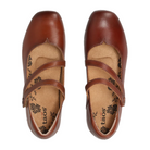 The Taos Women's Banter Cognac are brown leather Mary Jane shoes with two diagonal straps, floral-patterned tan insoles, arch support for comfort, and the TAOS brand name printed inside.
