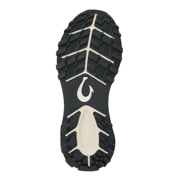 The OLUKAI Women's Makiki Lava Rock/Dark Shadow features a black and beige sole with a unique tread pattern, central curved logo, and deep grooves for reliable all-terrain traction.