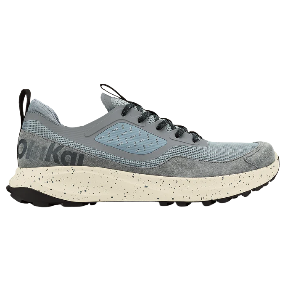 The OLUKAI Men's Makiki Grey is a light gray athletic sneaker with black laces, mesh and synthetic upper, black heel pull tab, speckled off-white sole, and partially visible branding—designed for all-terrain performance.