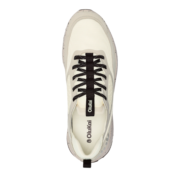 Top view of the OLUKAI Men's Makiki White sneaker in white and beige with black laces, speckled sole, and Olukai logo on tongue and insole—crafted for lightweight breathability and all-terrain comfort.