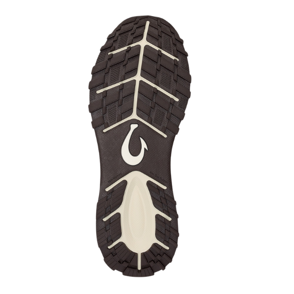 The OLUKAI Men's Makiki White features a brown and white lug-patterned sole with a hook-shaped logo at the center, designed for all-terrain traction, shown from the bottom against a white background.