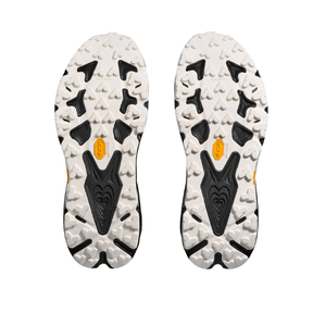 The HOKA Women's Speedgoat 7 Wide has white and black soles with rugged treads and yellow Vibram logos at the center.