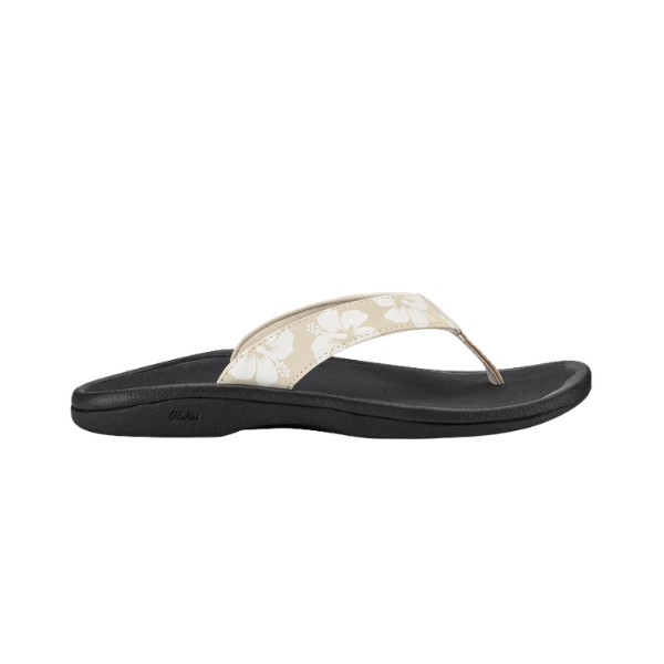 A side-profile of the OLUKAI Women's Ohana Tapa sandal in beige and white with a black sole on a white background.