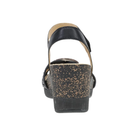 The Dansko Women's Stella Black is a black wedge sandal with a speckled cork heel, shown from the back.