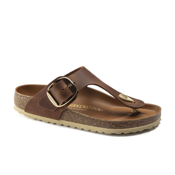 The BIRKENSTOCK Womens Gizeh Big Buckle Oiled Leather Cognac sandal features a cork sole, adjustable big buckle strap, and thong toe design, displayed against a white background.