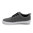 The Rival Mens Tilt Grey Chambray by RIVAL, INC. is a casual low-top sneaker with gray canvas, padded collar, black laces, and a white rubber outsole, shown in side profile against a plain white background.