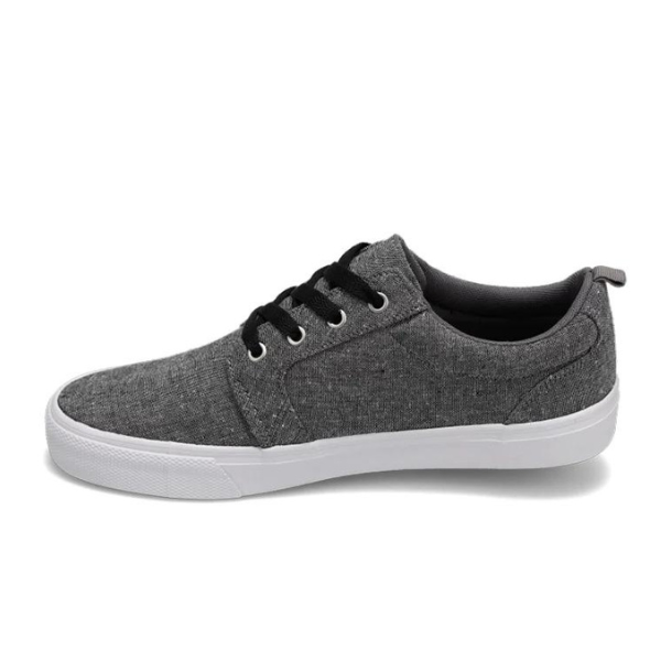The Rival Mens Tilt Grey Chambray by RIVAL, INC. is a casual low-top sneaker with gray canvas, padded collar, black laces, and a white rubber outsole, shown in side profile against a plain white background.