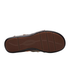 The image shows the sole of a Clarks Womens Wide Kitly Ave White sandal by CLARKS, featuring a textured brown rubber surface with crosshatch tread, the CLARKS logo embossed at the center, and black edges.
