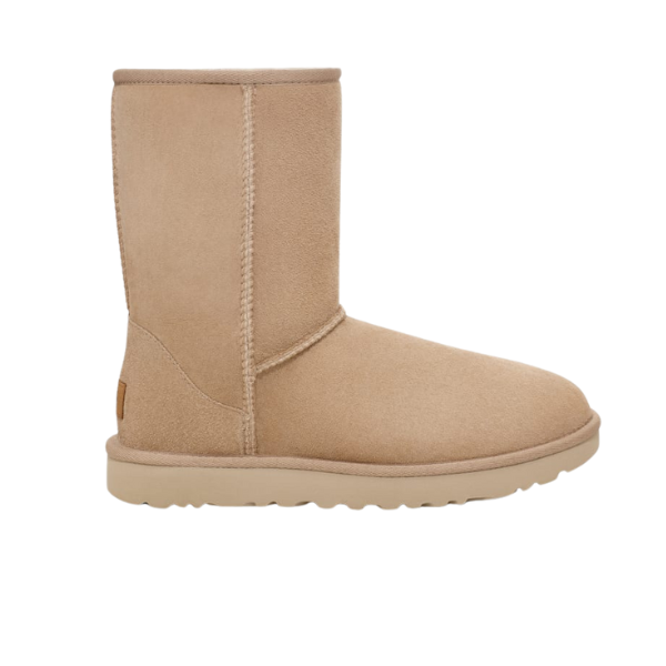 A single sand suede UGG Womens Classic Short II Boot by UGG, featuring visible stitching, a flat sole, and mid-calf height—designed for foot pain comfort—appears in profile against a white background.