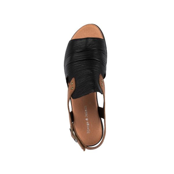 A top view of the Django & Juliette Womens Madis Black Leather sandal, featuring a textured black leather upper, brown sides, open toe, tan footbed with white branding, and a brown ankle strap with buckle.