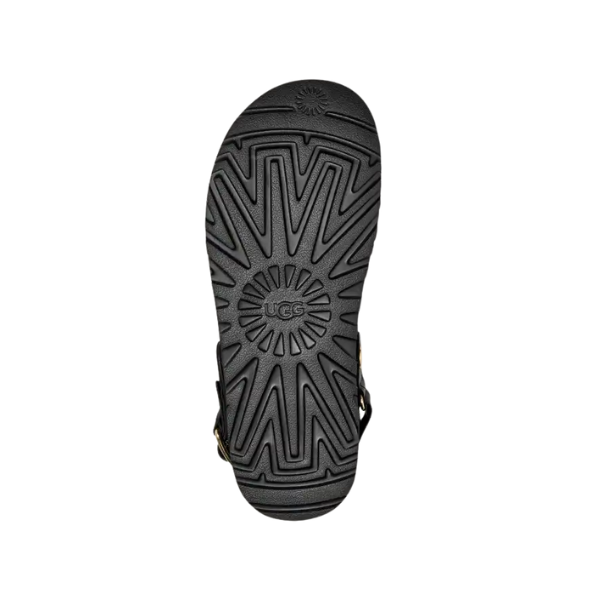 UGG Women's Goldenstar Villa Black sandal shown from the sole, displaying a sunburst tread and embossed UGG logo. Made with nubuck leather and an adjustable backstrap, presented on a white background.