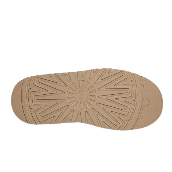 The tan platform outsole of the UGG Womens Tazz Slippers Sand features a circular pattern with radiating grooves for traction, and displays the UGG logo at the center, highlighting this quality footwear.
