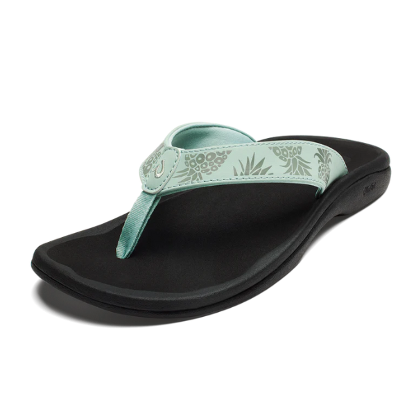 The OLUKAI Womens Ohana flip-flop in Mint / Swell Hua has a black sole, a light teal floral-patterned strap, and an anatomical footbed, shown on a white background.
