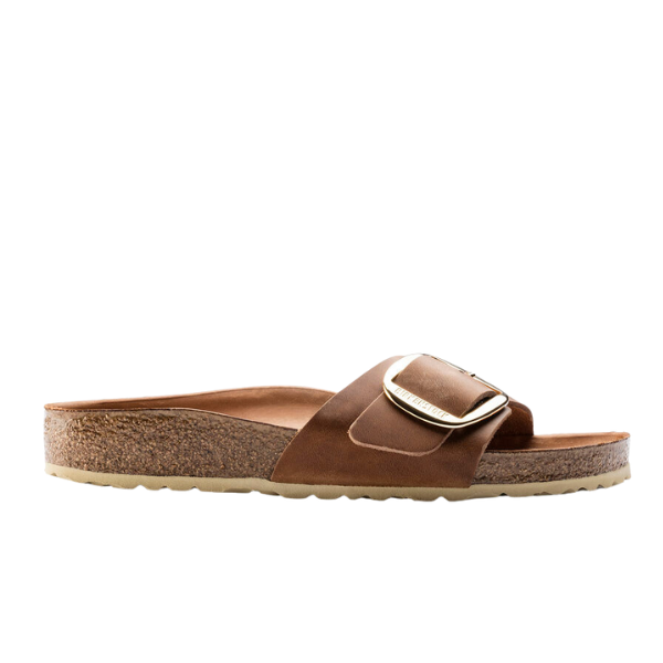 The BIRKENSTOCK Womens Madrid Big Buckle Cognac sandal features a cork footbed, Wide brown strap with a large gold buckle, and flat rubber sole, shown in side profile on a white background.