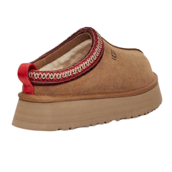 The UGG Womens Tazz Slippers Chestnut feature a tan slip-on design with a thick platform sole, cozy UGGplush™ lining, red and white trim at the opening, and a red heel pull tab—showcasing signature UGG style.