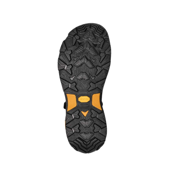 The image displays the black rubber sole of the Teva Mens Grandview Max Hiking Sandal by Teva, highlighting its rugged tread and central yellow Vibram MegaGrip logo, set against a plain white background.