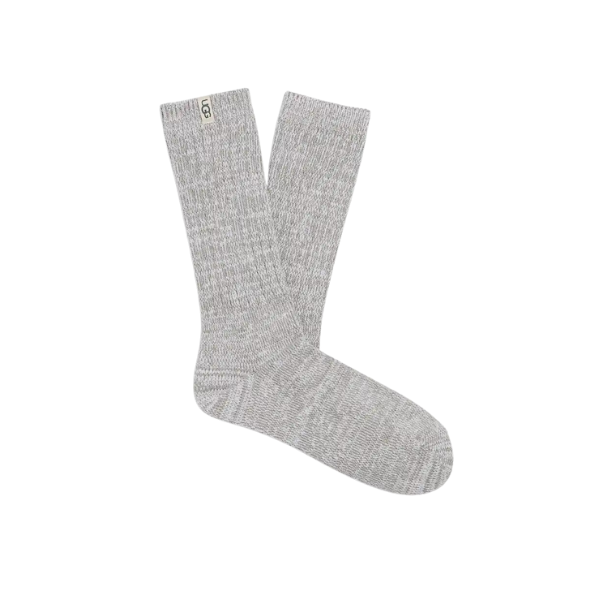 The UGG Women's Rib Knit Slouchy Crew Sock in grey/black features a rib knit design, slouchy fit, and a beige UGG logo tag near the top. One sock is laid flat while the other slightly overlaps it.