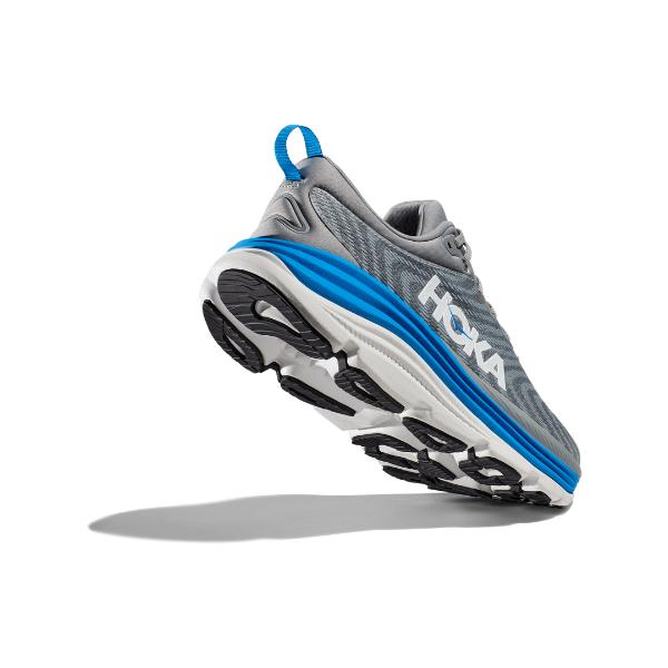 The HOKA Mens Gaviota 5 Wide in Limestone/Blue is shown midair against a white background, viewed from the back and side to highlight the sole, HOKA logo, and supportive H-Frame technology designed for plantar fasciitis.