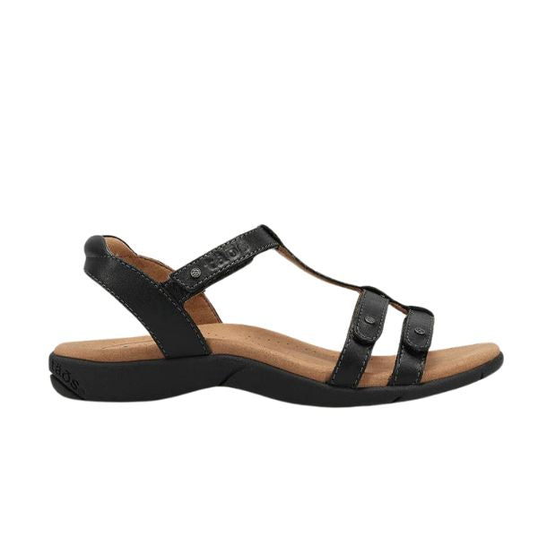 The TAOS Womens Trophy 2 Black Emboss sandal features a black leather upper, low heel, open toe, adjustable straps, and a cushioned tan footbed with arch support for comfort.
