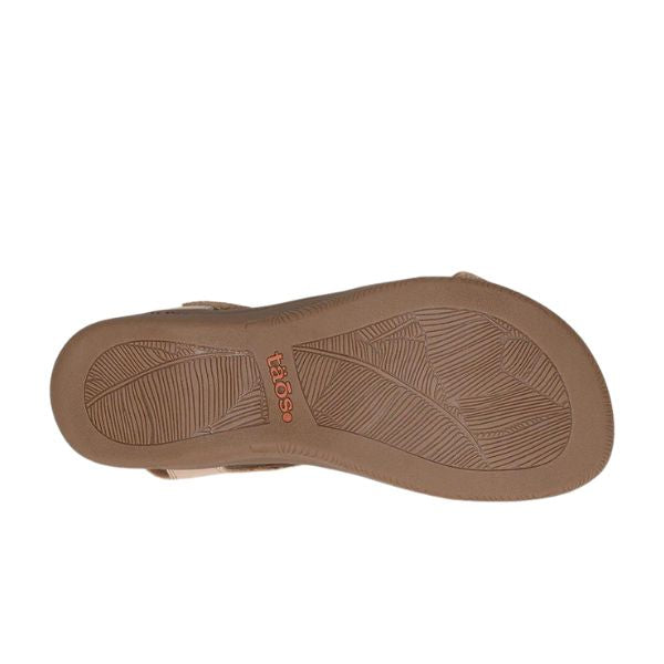 The image shows the sole of the TAOS Womens The Show Stone sandal, featuring a leaf-like tread pattern and taos in orange near the heel, highlighting its supportive arch support design.